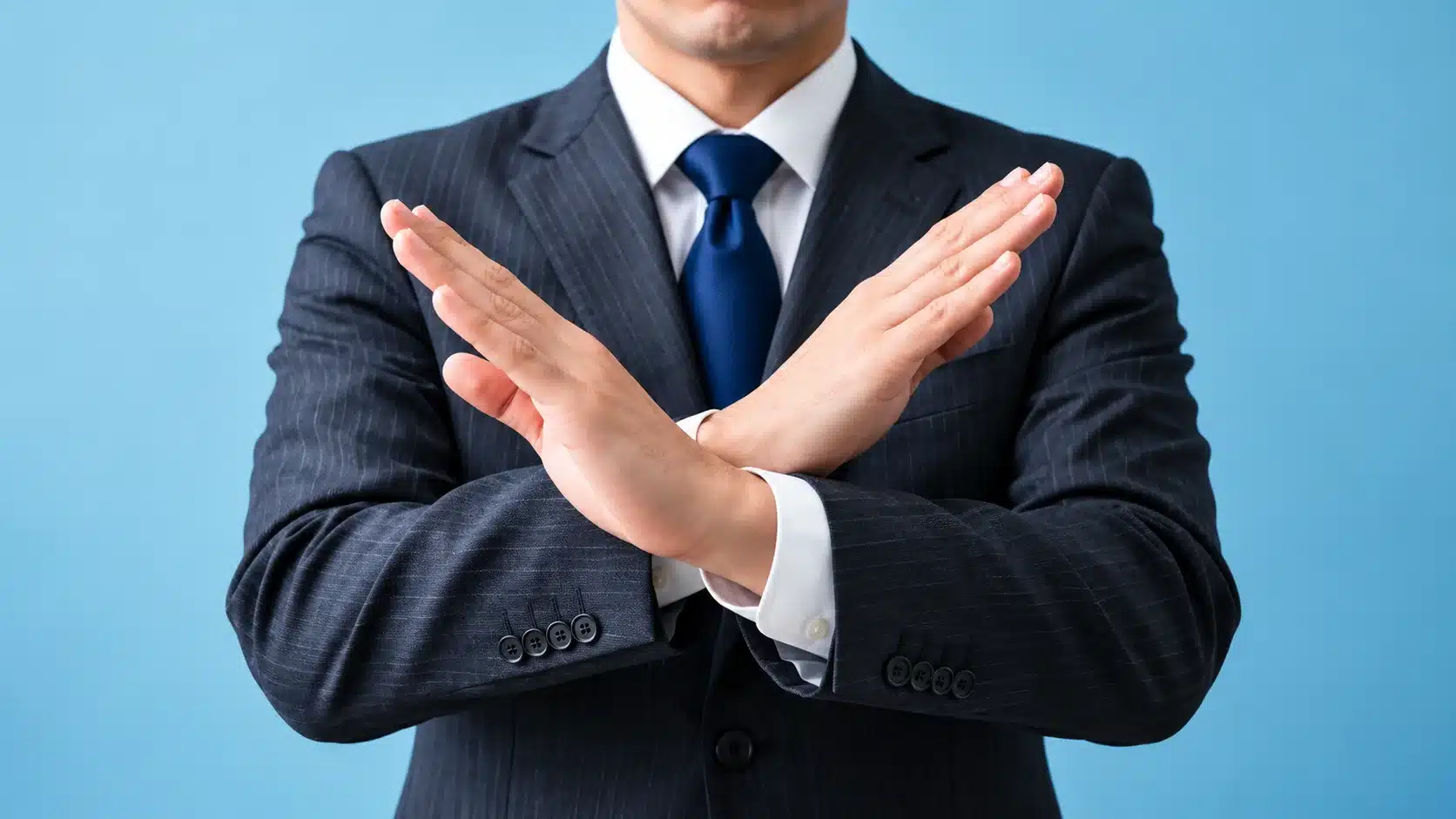 Man in a suit crossing his arms in a stop gesture